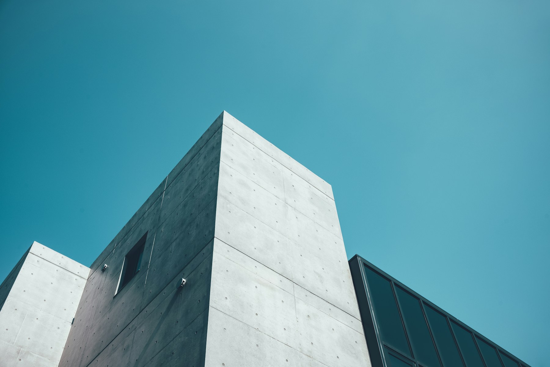 A sharply angled concrete building framed against a teal blue sky
